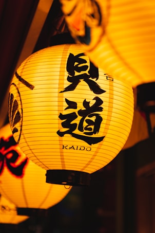 A glowing lantern with Japanese characters and the word 'Kaido' written on it, surrounded by other similar lanterns. The background is dark, highlighting the warm yellow glow of the lanterns.