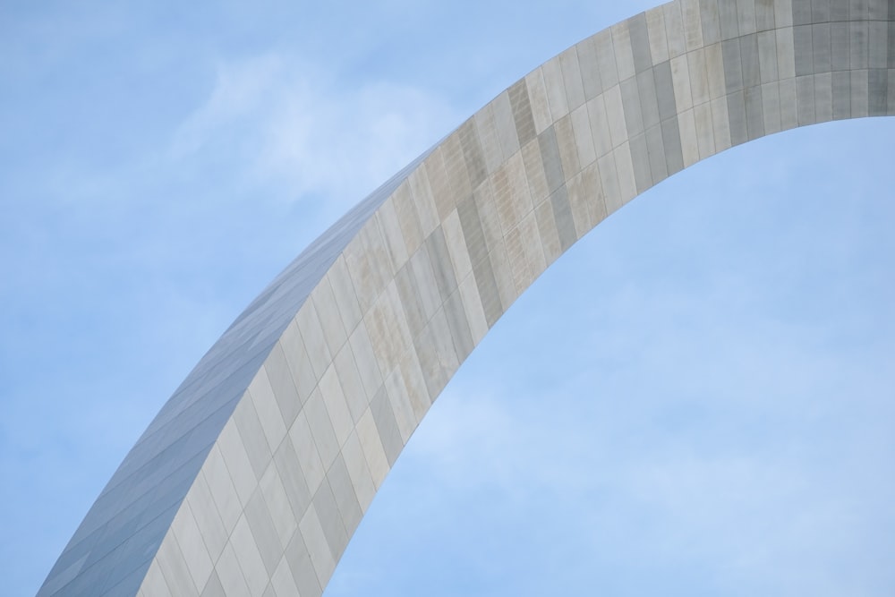 a plane flying over the arch of a building