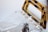 A transparent plastic handbag with a brown tortoiseshell-patterned handle and gold rivets along the top edge. The clear material creates a sleek and modern look, reflecting light subtly. The design combines minimalist and contemporary styles.