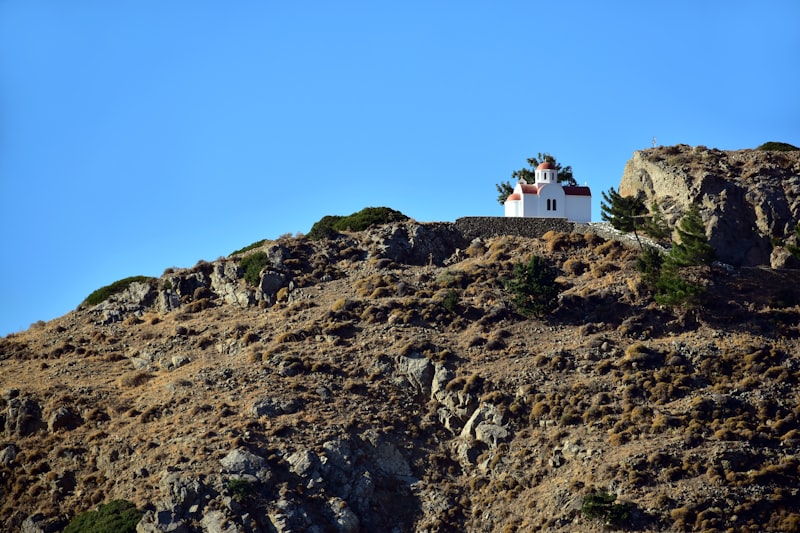 a small white house on a rocky hill