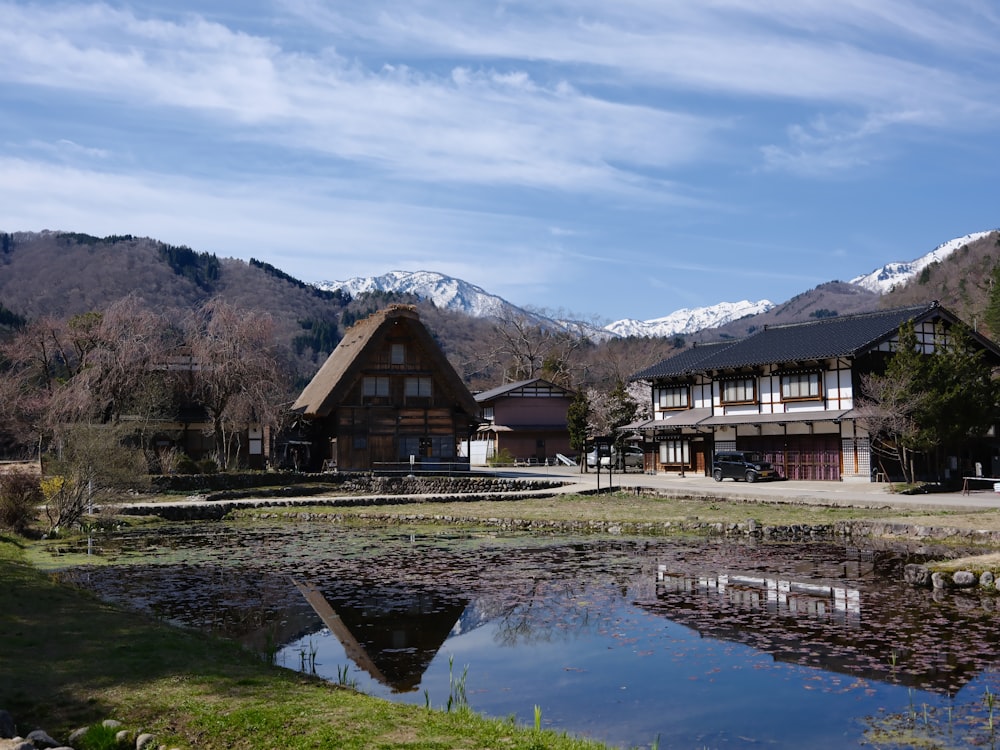 a house with a pond in front of it and mountains in the background
