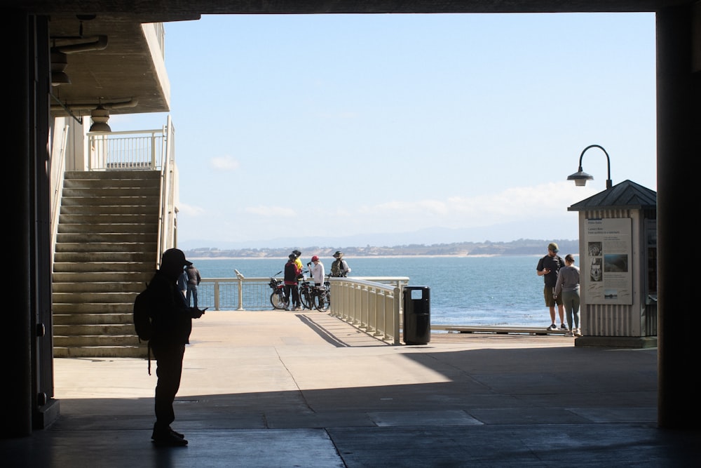 a group of people standing on a pier next to the ocean