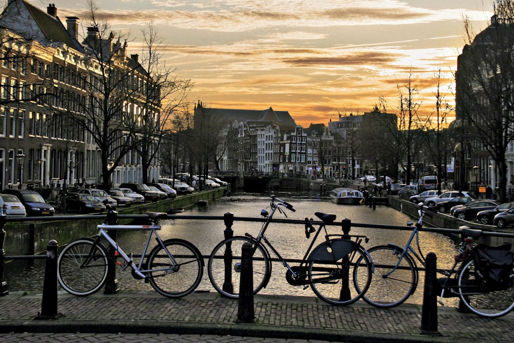 bicycles are parked on the railing of a canal