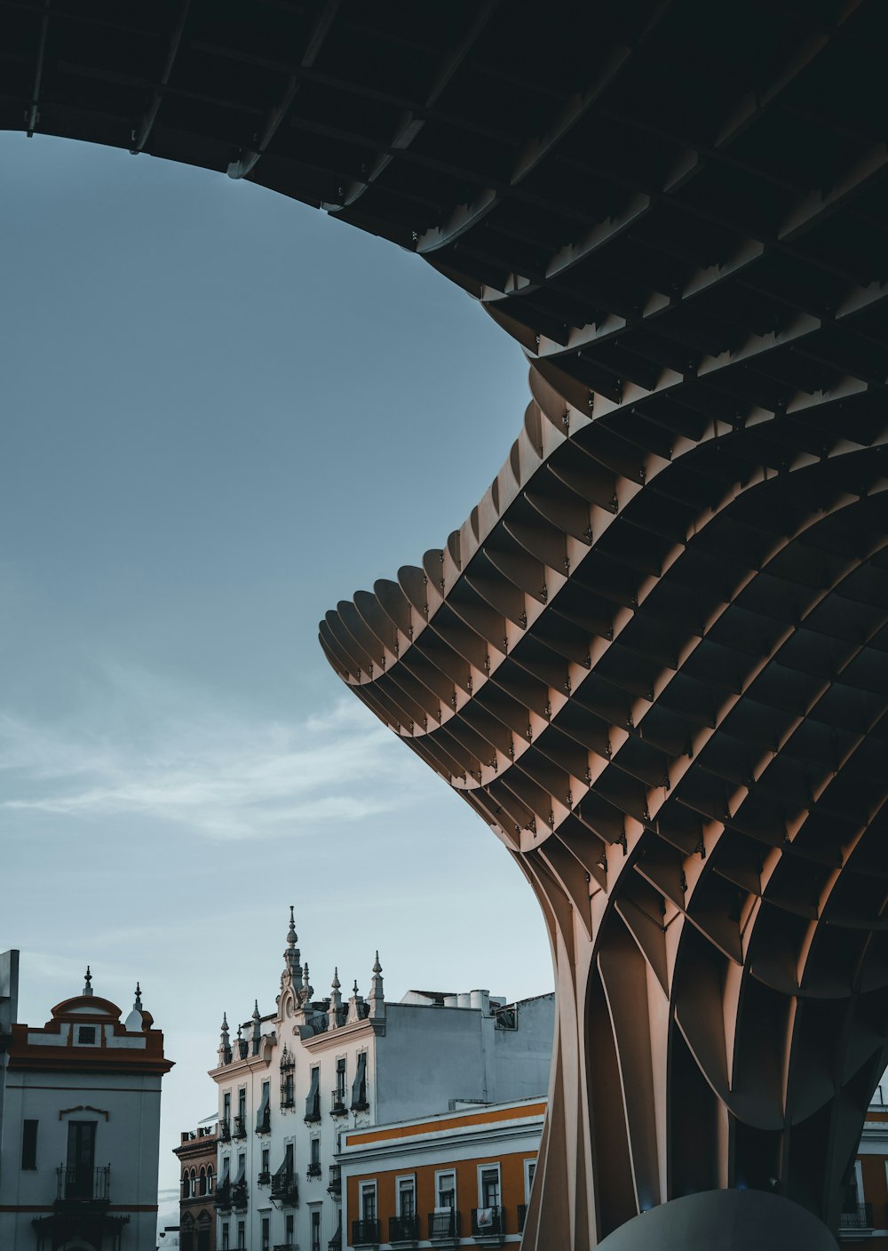 a building with a curved roof and a clock tower in the background