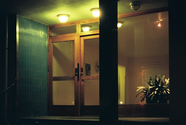 An inviting entrance with black-framed glass doors and soft ivory accents glowing in ambient light.