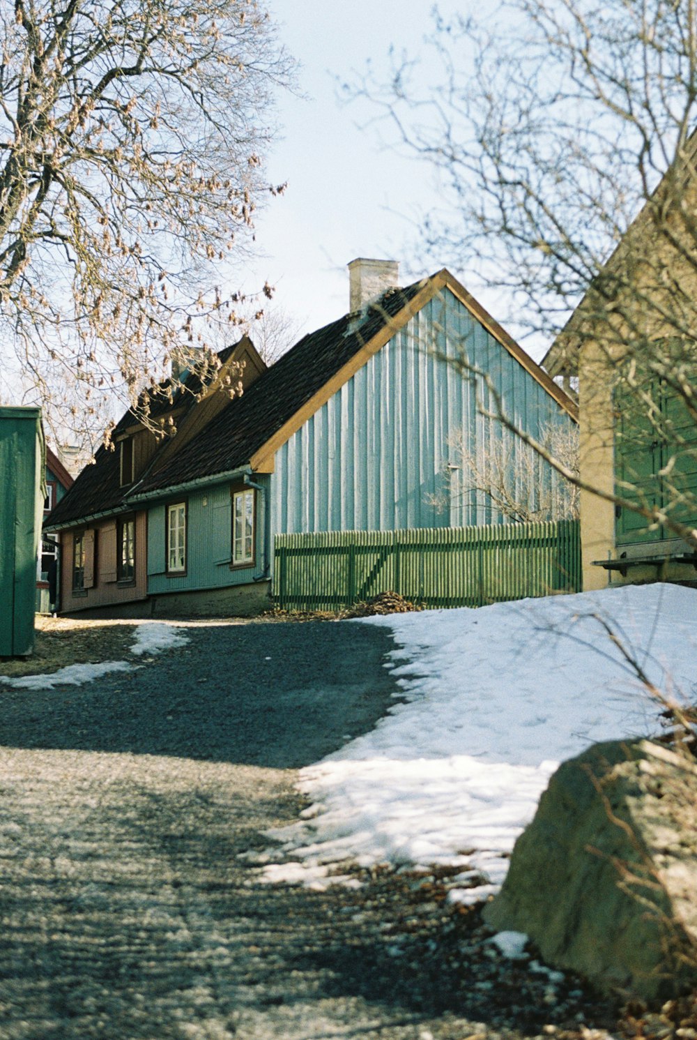 a house with a green roof next to a snow covered road