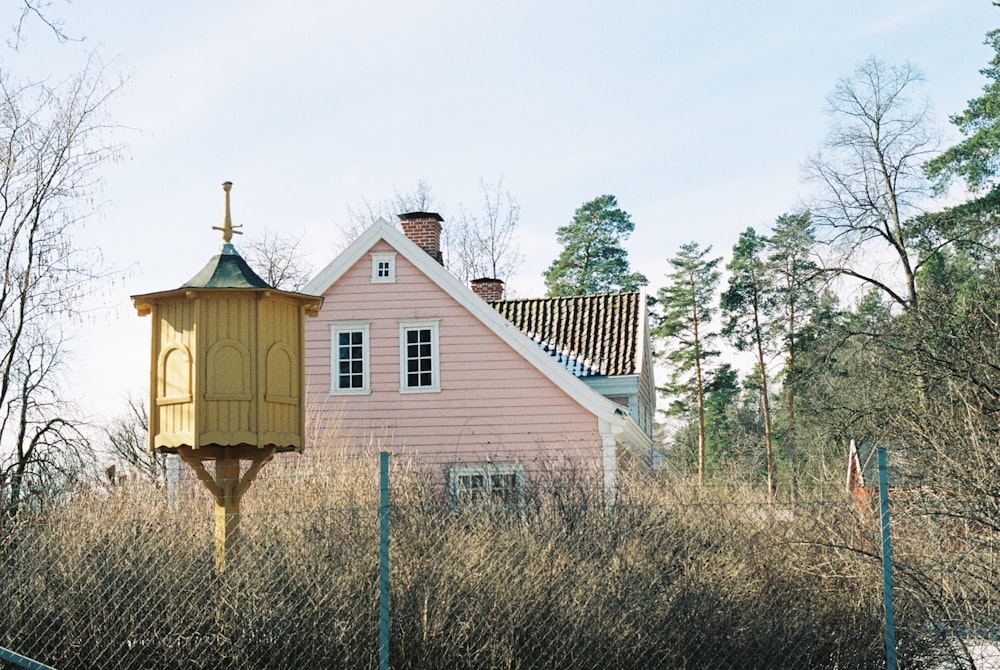 a pink house with a bird house on top of it