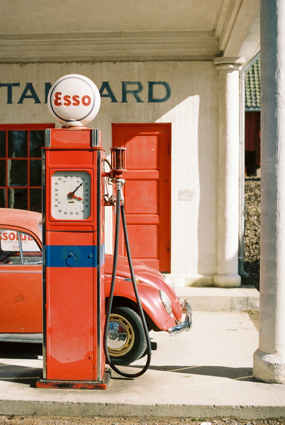 um carro vermelho estacionado ao lado de uma bomba de gasolina