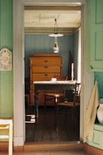 a room with a table, chairs, and a dresser