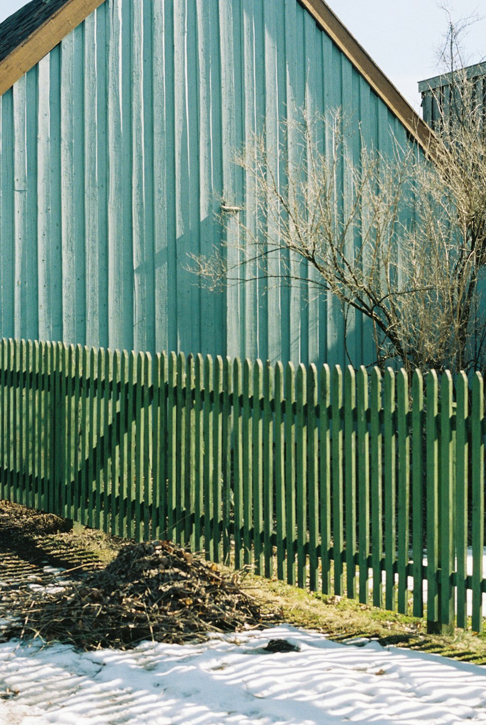 a green building with a wooden fence in front of it