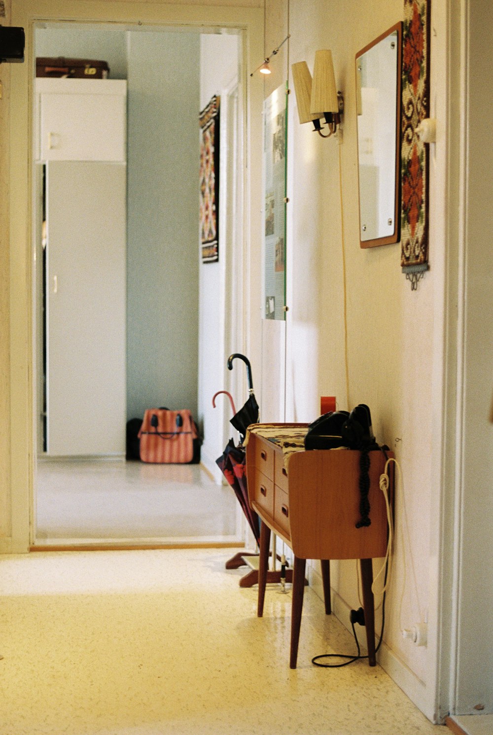 a hallway with a table, mirror and umbrella