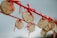 Wooden heart-shaped locks with inscriptions hang on a red rope. The locks are tied with red ribbons, and one is prominently visible with the words 'Love You' and a date written on it. The background is softly blurred, emphasizing the objects and creating a sentimental atmosphere.
