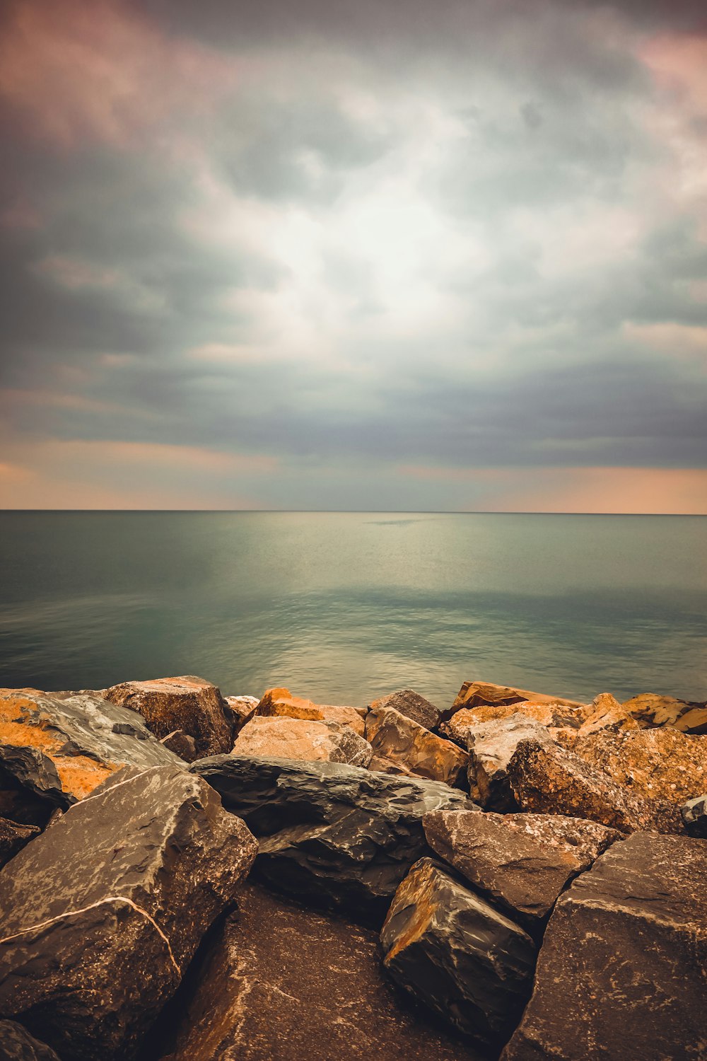 a rocky beach with rocks and water under a cloudy sky