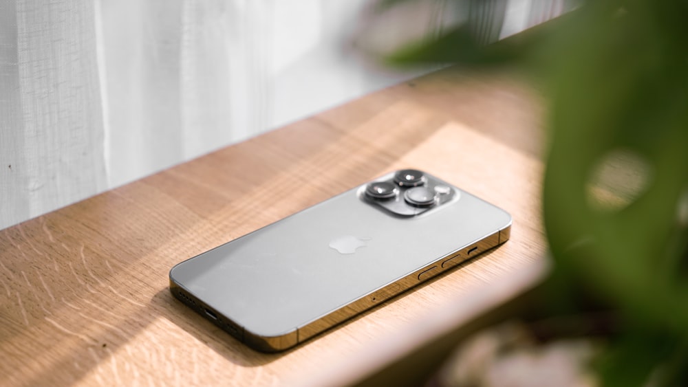 a silver iphone sitting on top of a wooden table
