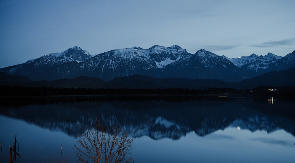 a mountain range is reflected in the still water of a lake