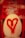 A bathroom stall features a toilet with a white seat, upon which a large red heart is spray-painted. The background shows walls covered with various pieces of graffiti in different colors and styles.