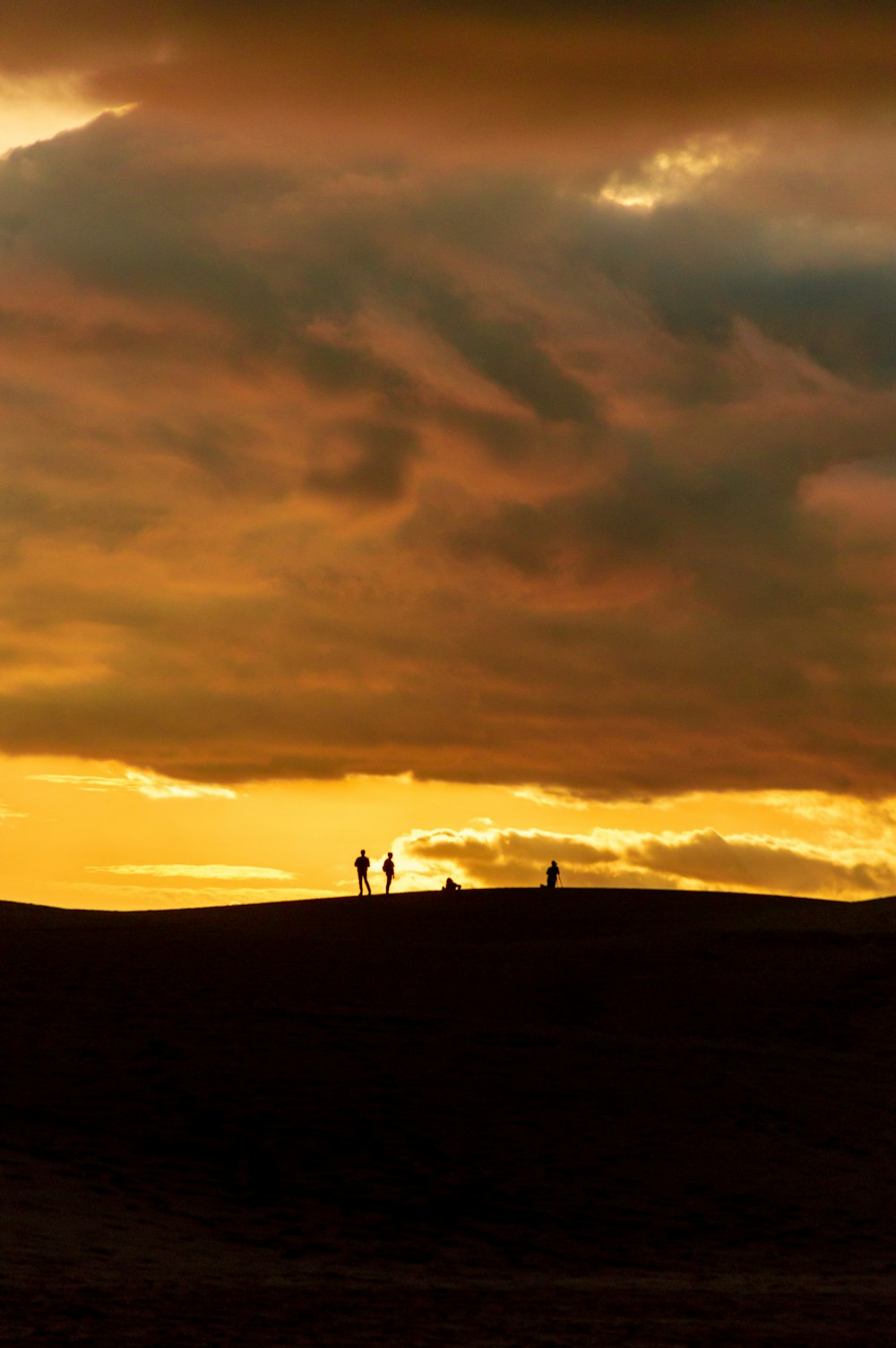 a couple of people standing on top of a hill under a cloudy sky
