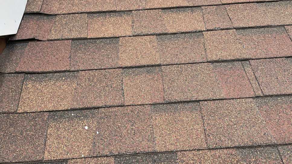 Close-up of a skilled roofer carefully installing asphalt shingles on a sunny Los Angeles rooftop.