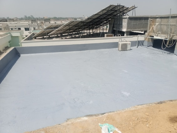 A technician inspecting an air conditioning unit on a rooftop in a sunny cityscape.