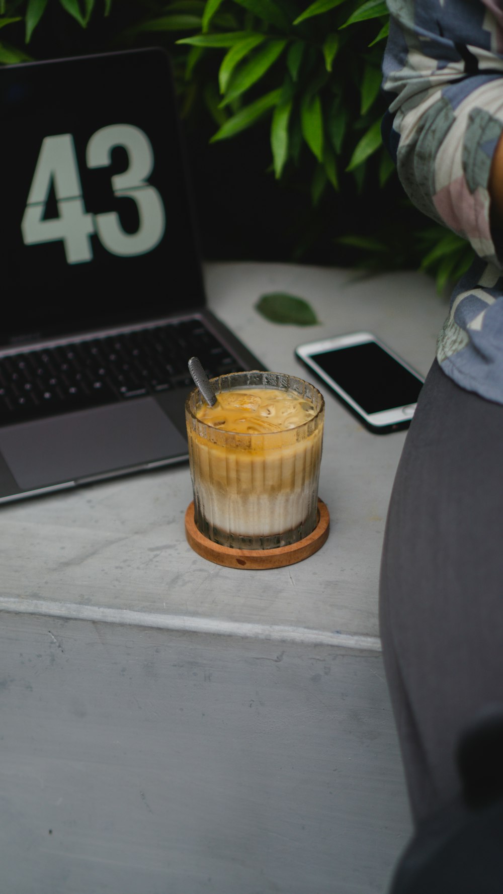 um copo de líquido ao lado de um laptop em uma mesa
