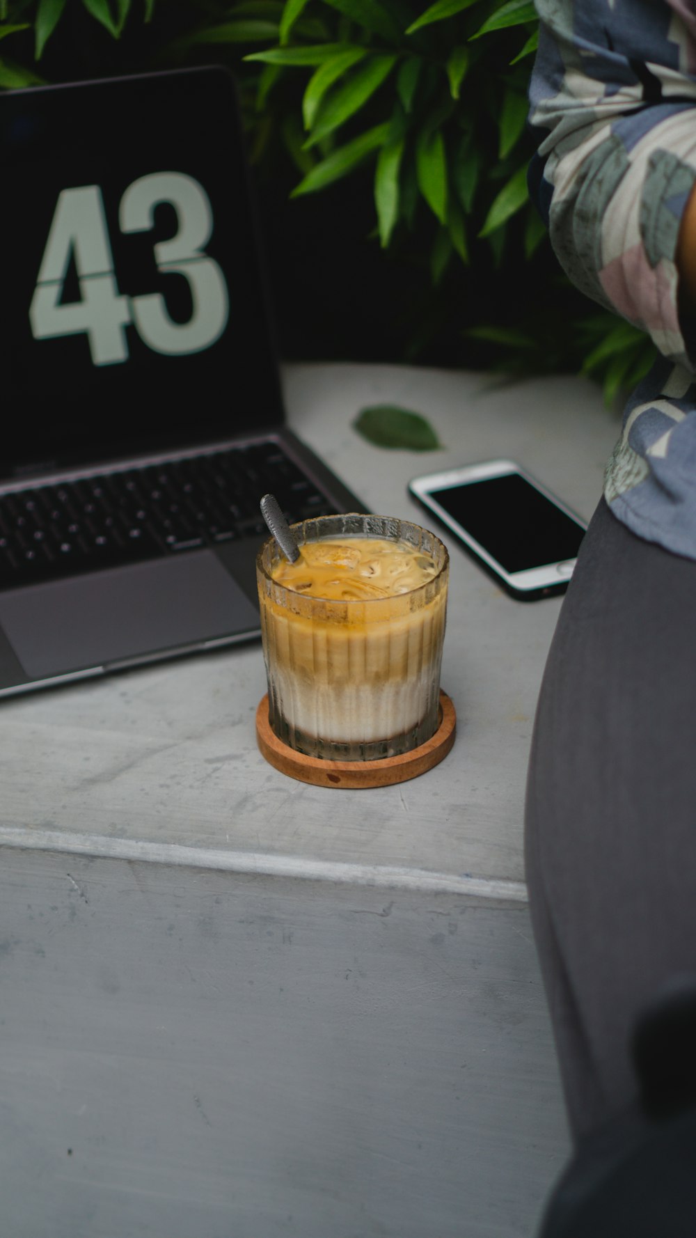 Un vaso de líquido junto a una computadora portátil sobre una mesa