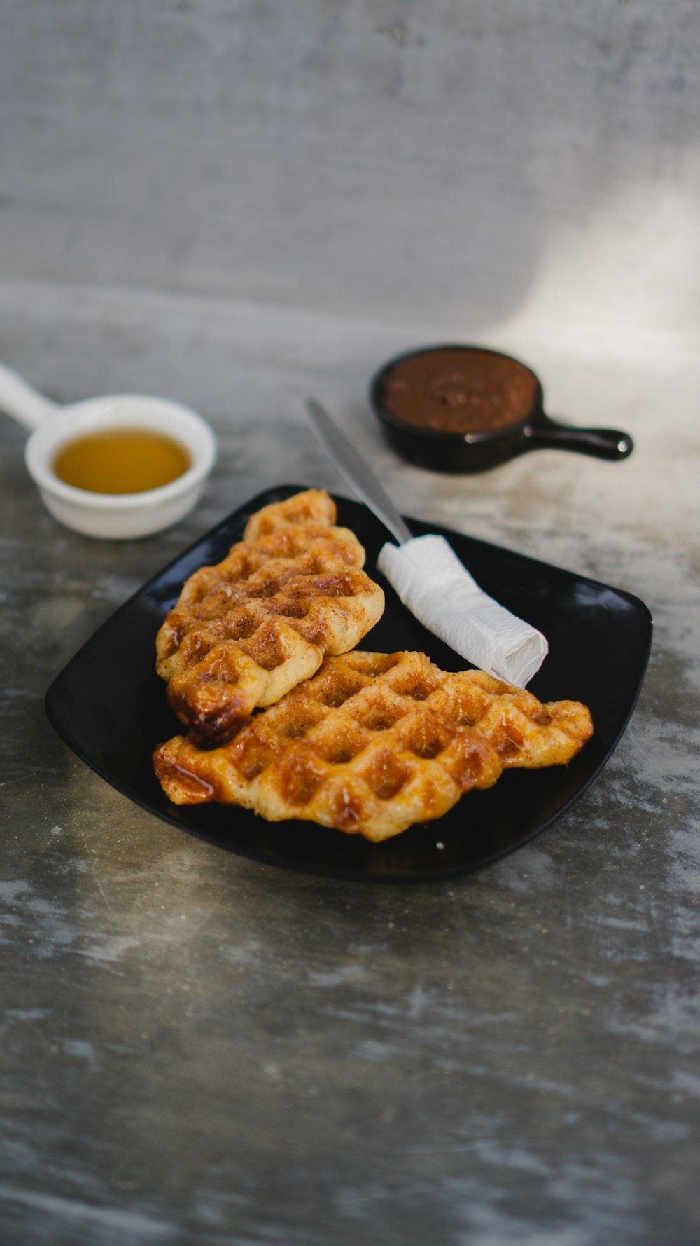 a plate of waffles and a bowl of dipping sauce