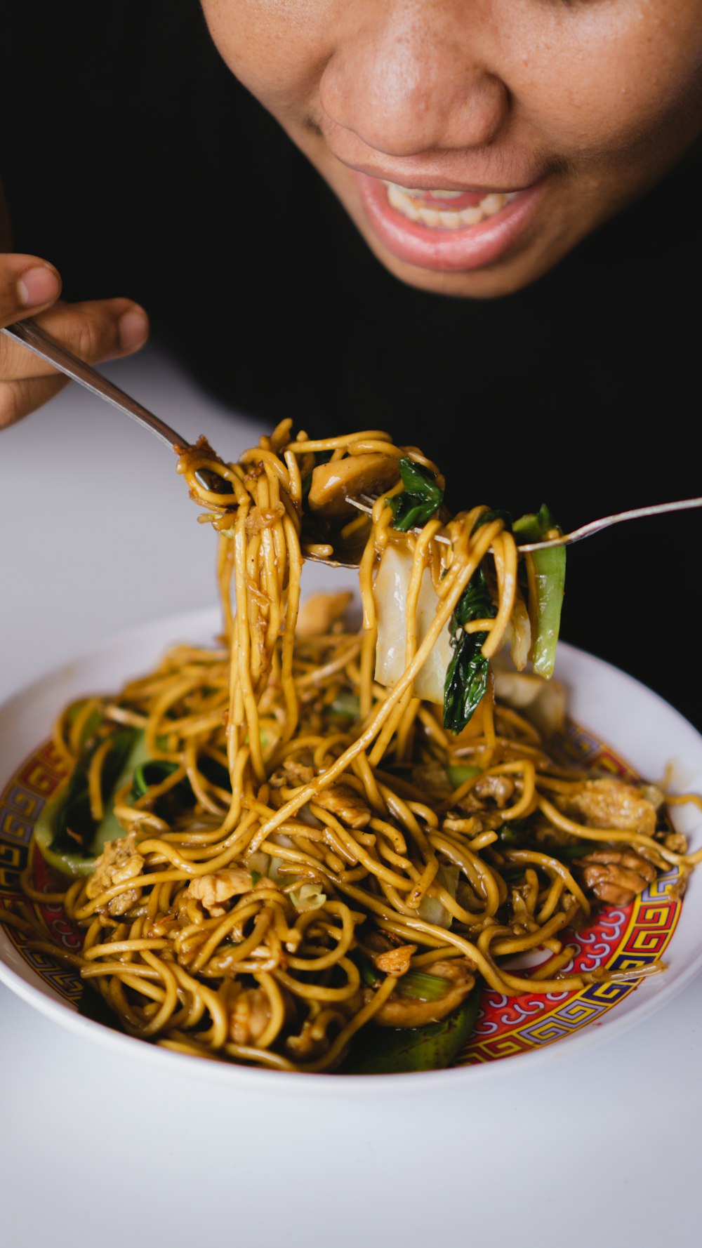 a woman eating a bowl of noodles with chopsticks