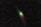 A comet with a bright green glow at the head and a long, trailing tail is surrounded by a vast expanse of stars in the night sky.
