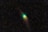 A comet with a bright green glow at the head and a long, trailing tail is surrounded by a vast expanse of stars in the night sky.