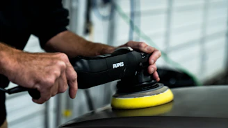 a man sanding a car with a polisher
