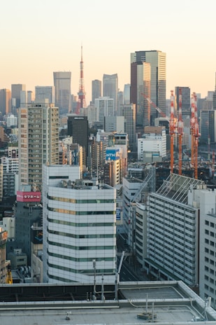 A panoramic view of Tokyo's skyline at sunrise with Mount Fuji in the distance, bathed in warm golden light highlighting sleek glass skyscrapers.