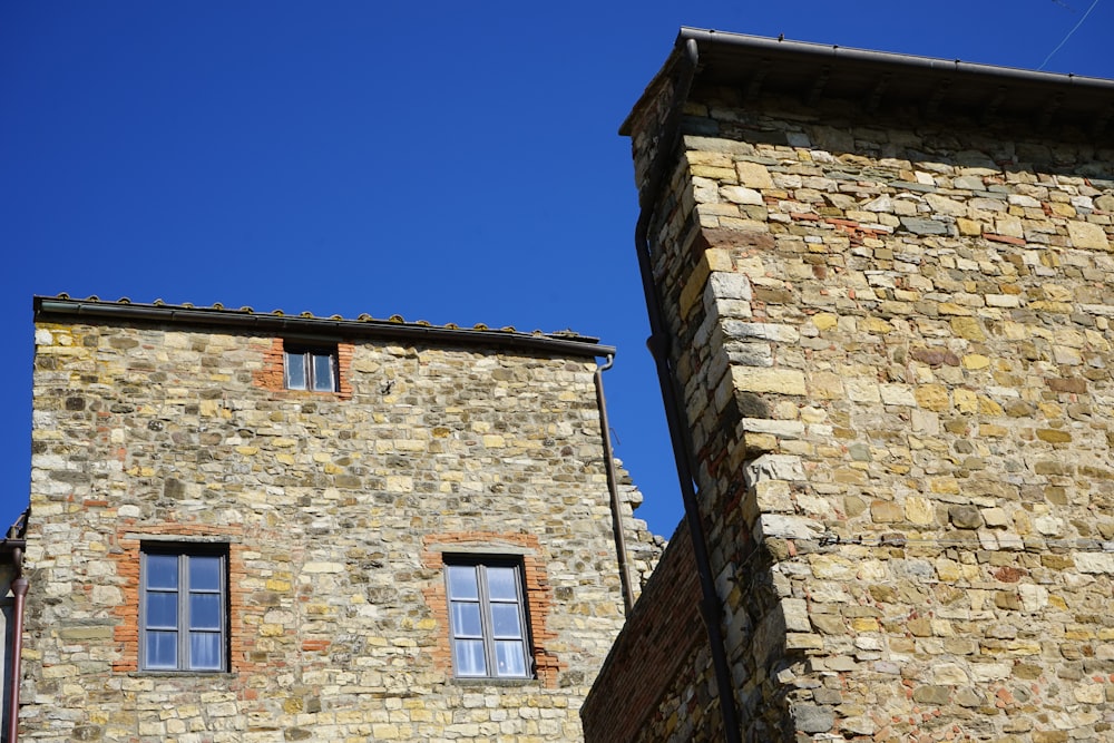a stone building with two windows and a sky background