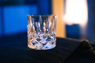 A sleek glass tumbler catching sunlight on a minimalist desk next to a laptop.