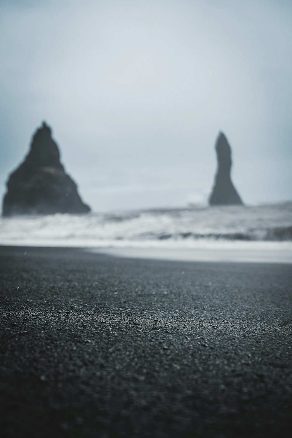 a black sand beach with a rock formation in the background