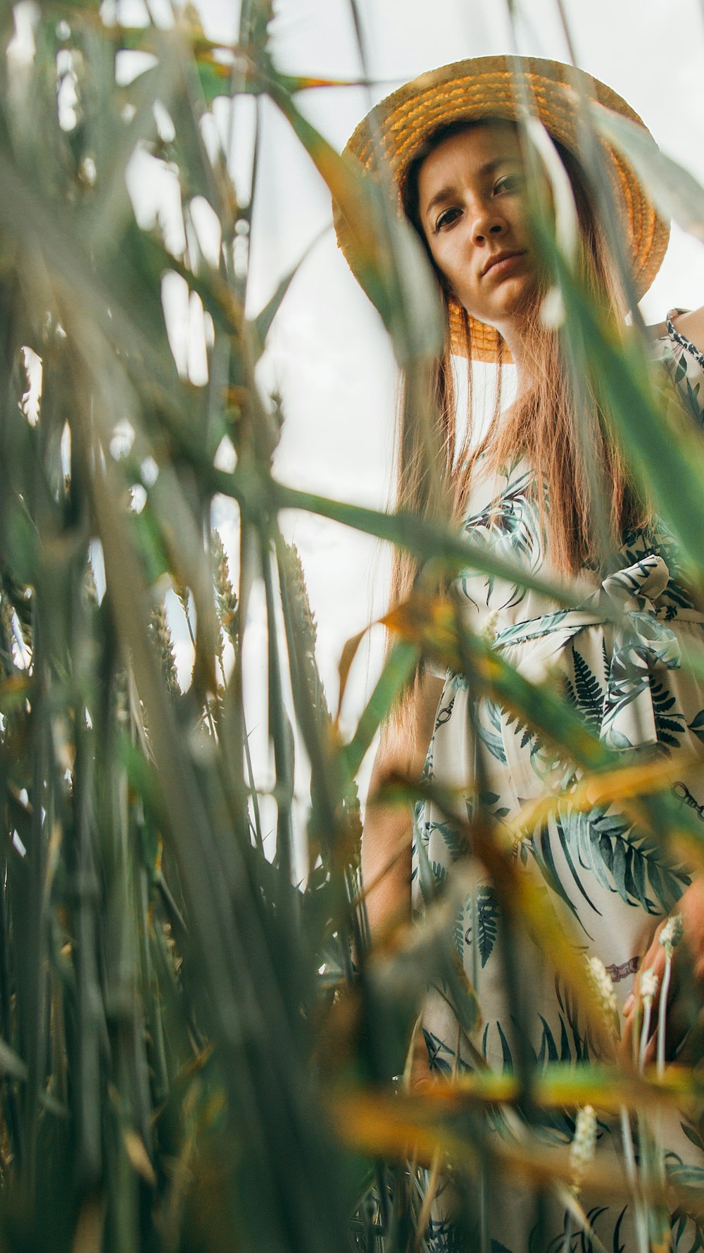 a woman wearing a straw hat standing in a field