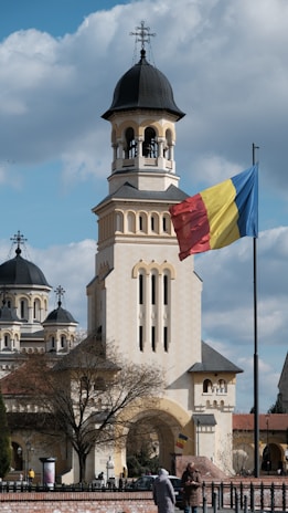 a flag flying in front of a building with a clock tower