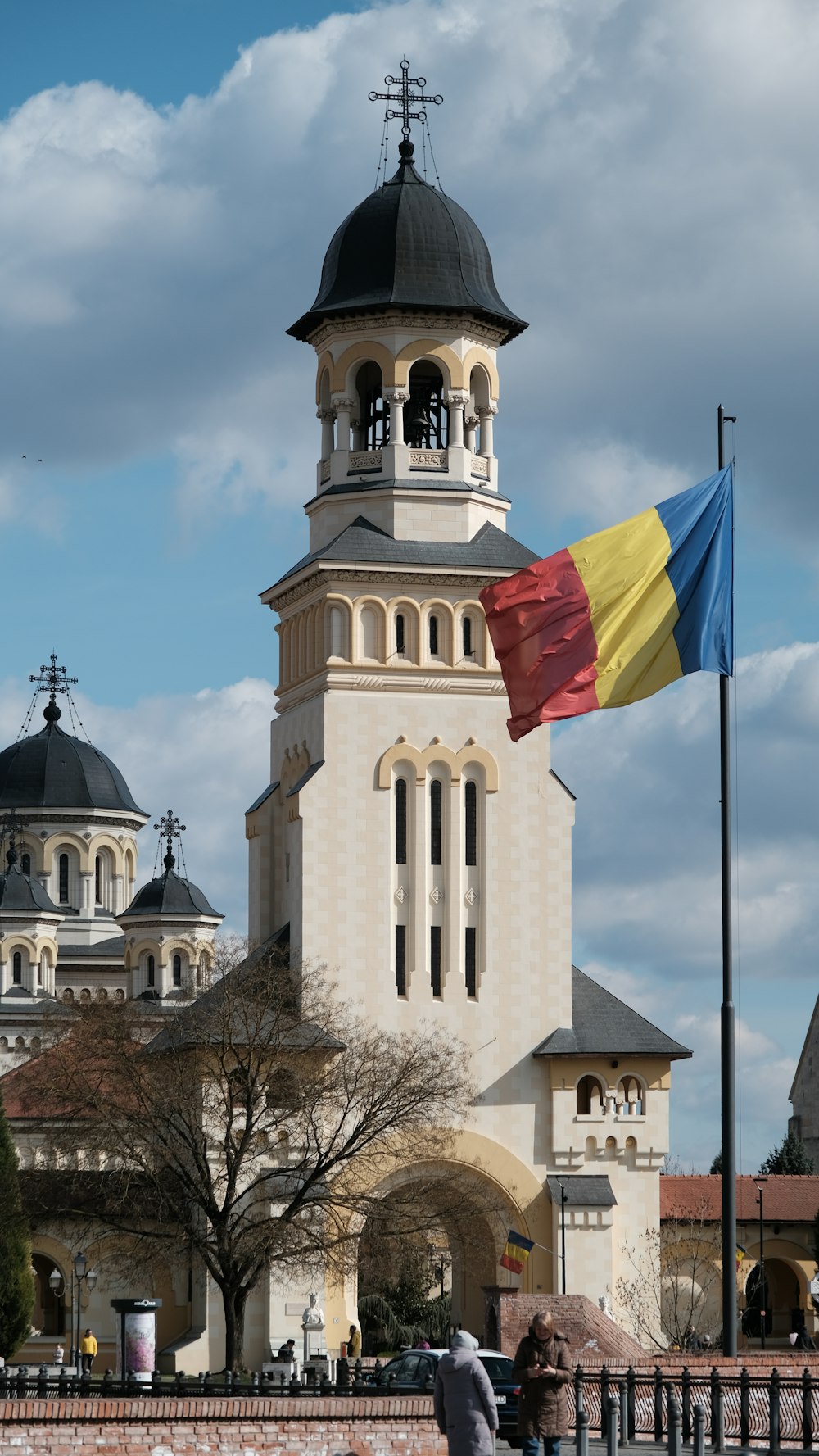 Un drapeau flottant devant un bâtiment avec une tour de l’horloge