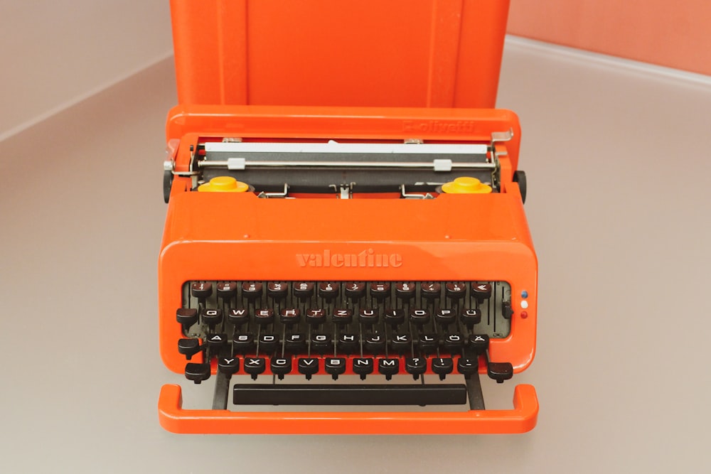 una macchina da scrivere arancione seduta sopra un tavolo