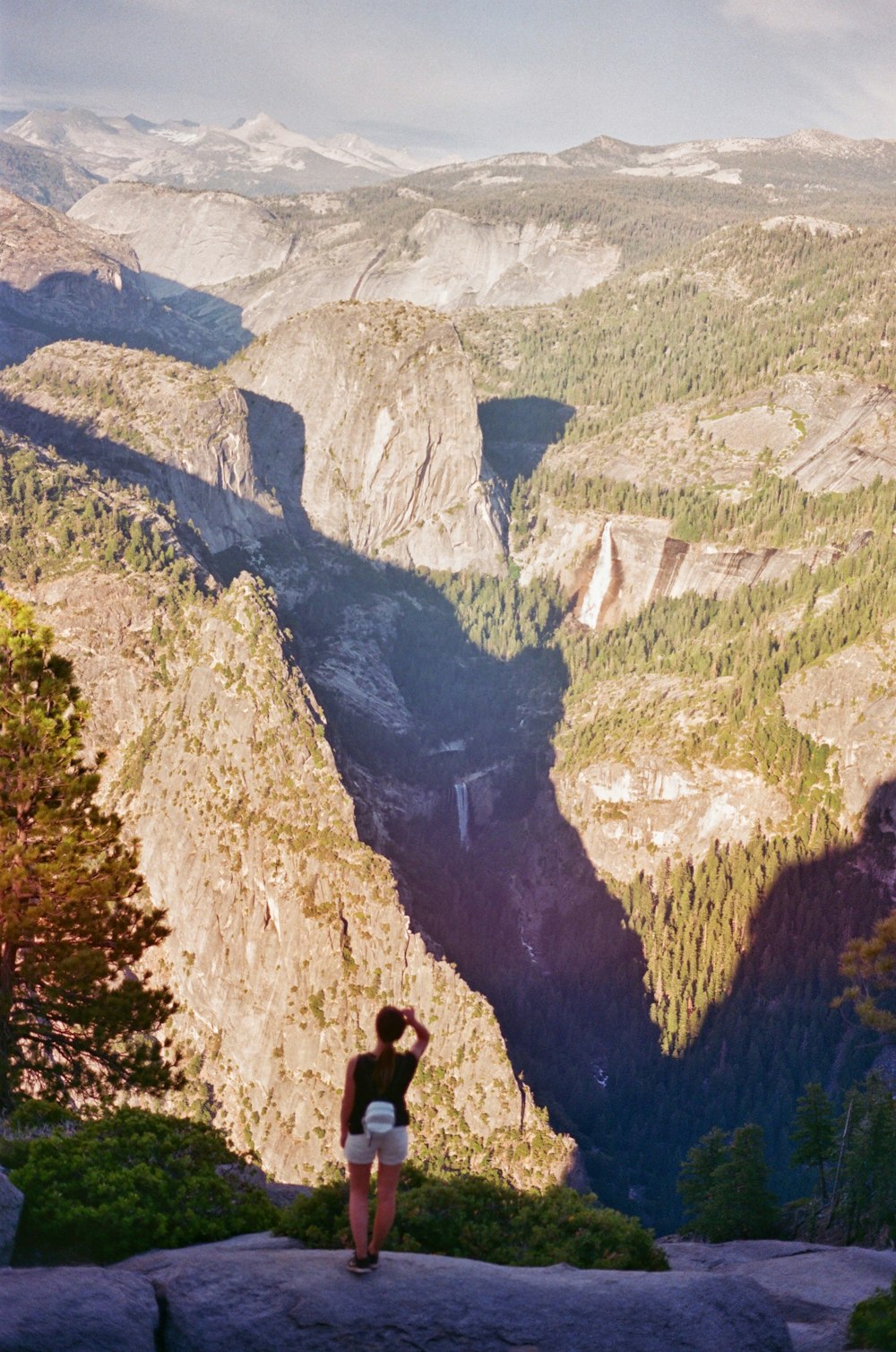 a woman standing on top of a mountain overlooking a valley