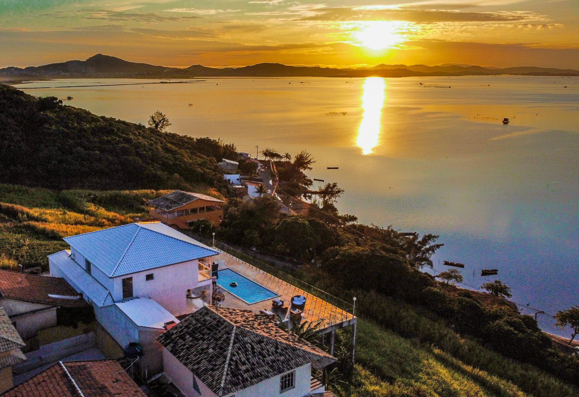 A serene sunset view over the calm waters of Prado reservoir with Casa Paraíso nestled among lush greenery.