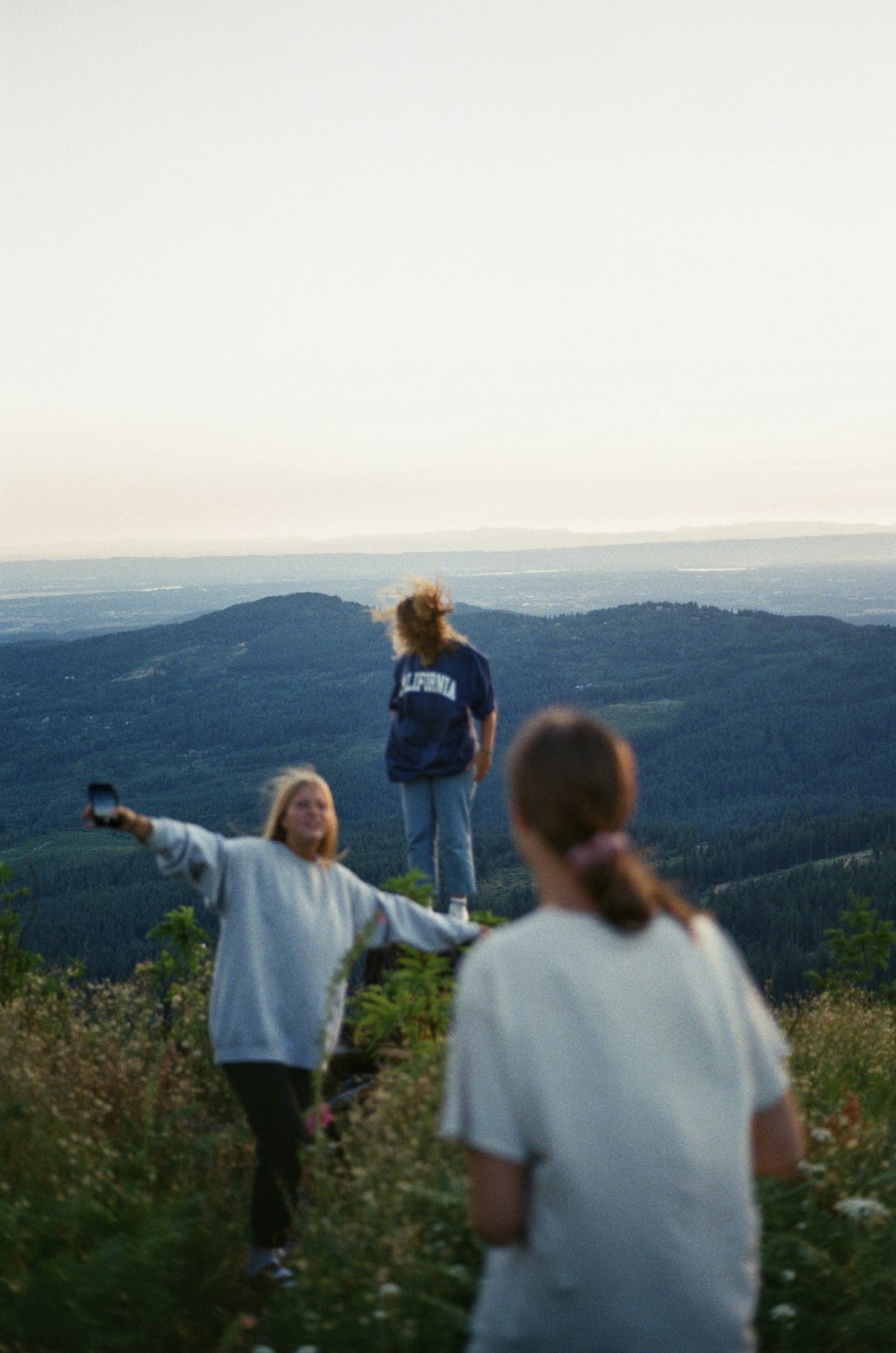 a group of people standing on top of a lush green hillside