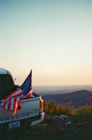 A patriotic t-shirt draped over a vintage pickup truck’s tailgate with an open highway in the background.