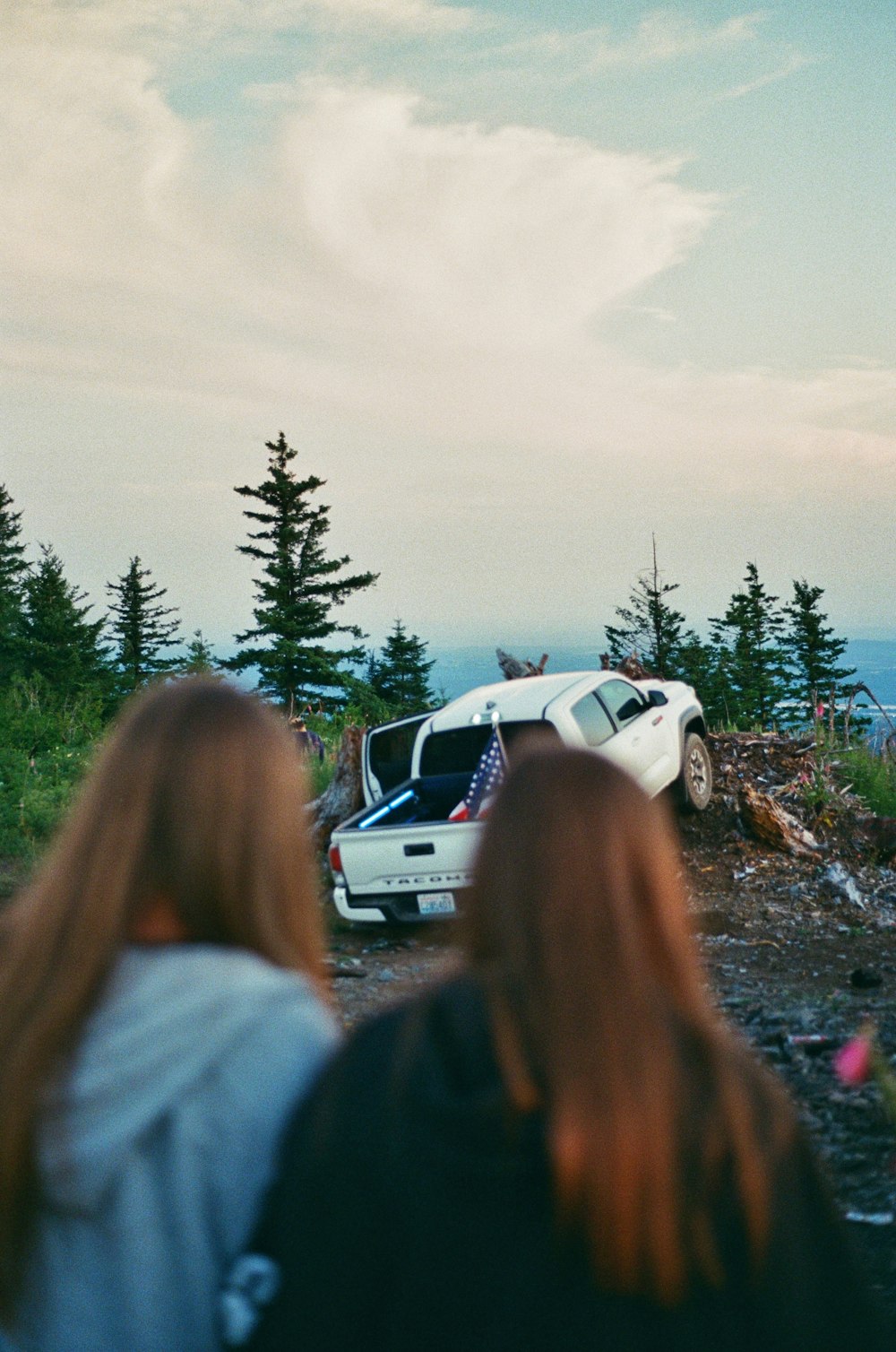 two people are walking towards a car that is on the side of a hill