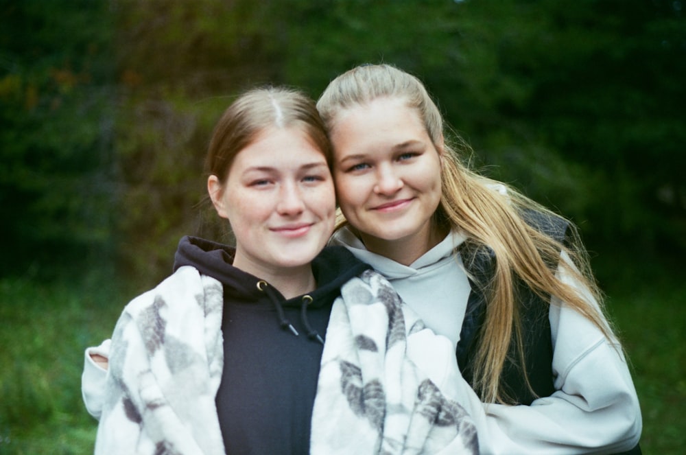 two girls are hugging each other in the woods