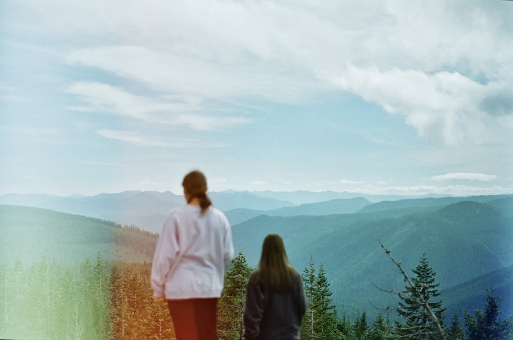 a couple of people standing on top of a hill