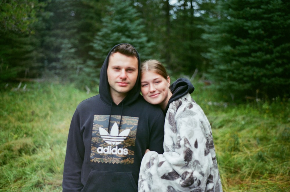 a man and a woman are standing in the woods