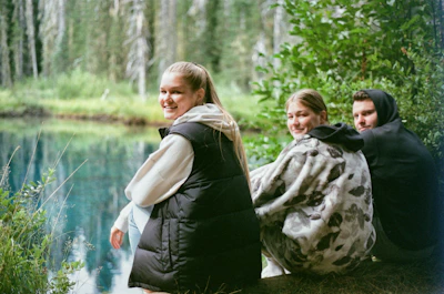 A group of happy travelers enjoying a scenic picnic by a peaceful lake surrounded by South Indian forests.