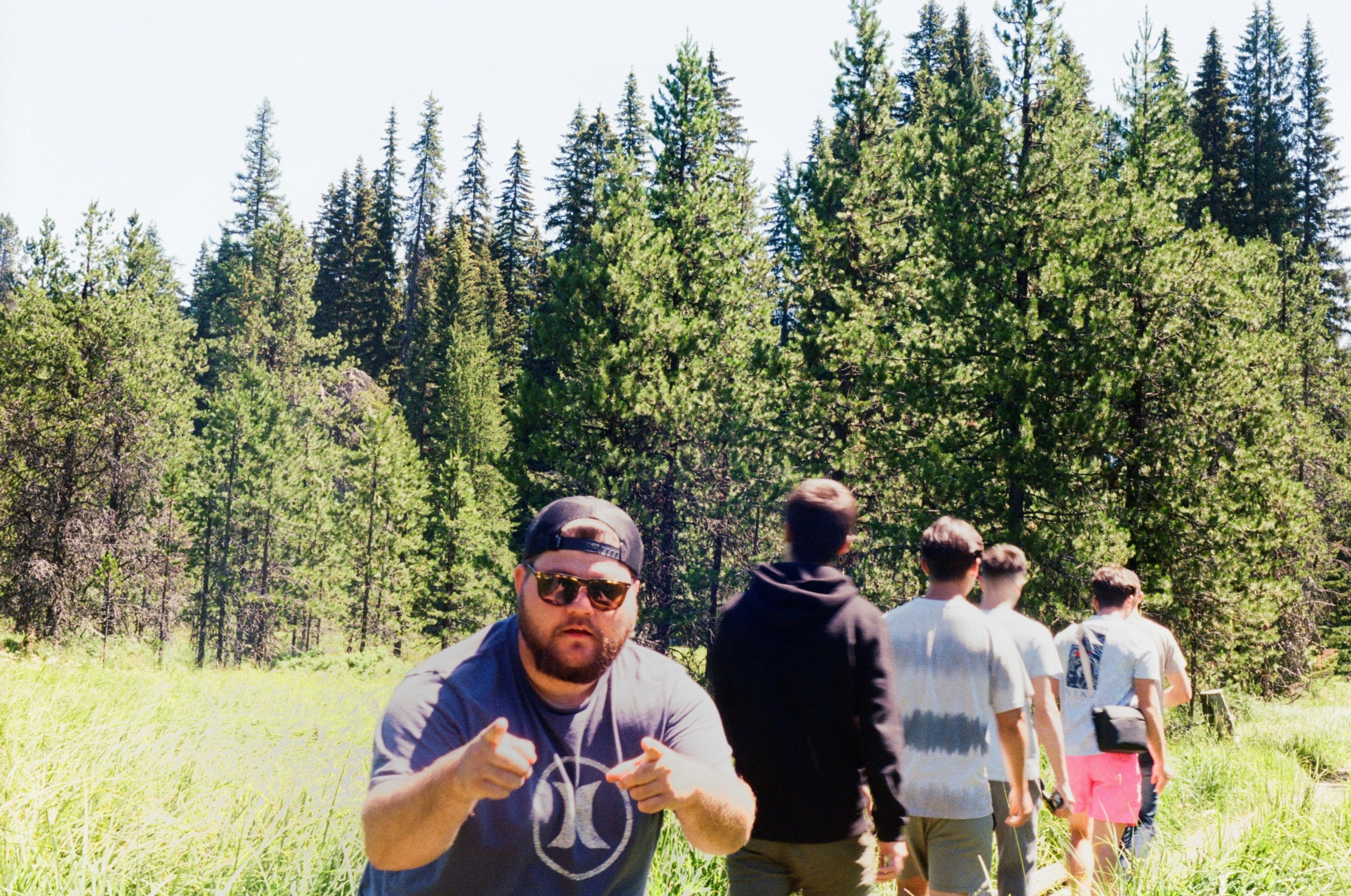 a group of people standing in a field with trees in the background