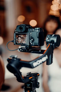 a camera attached to a tripod with a woman in the background