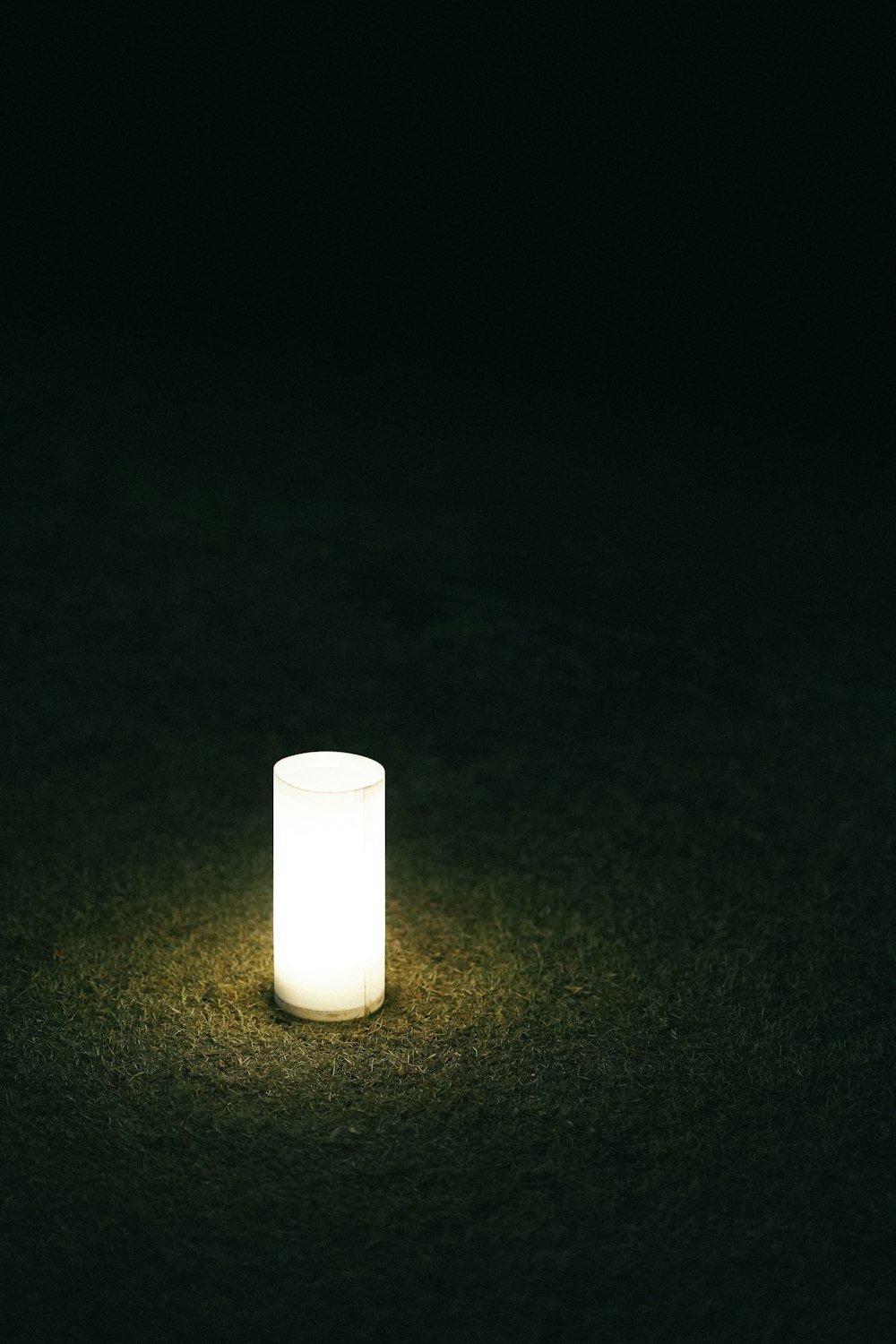 a lit candle sitting on the ground in the dark